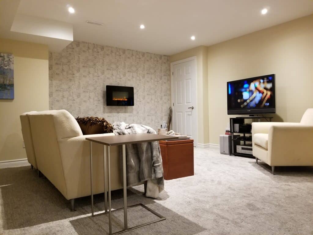 Birch bark inspired wallpaper, an electric fireplace, and broadloom feature in this renovated basement project.