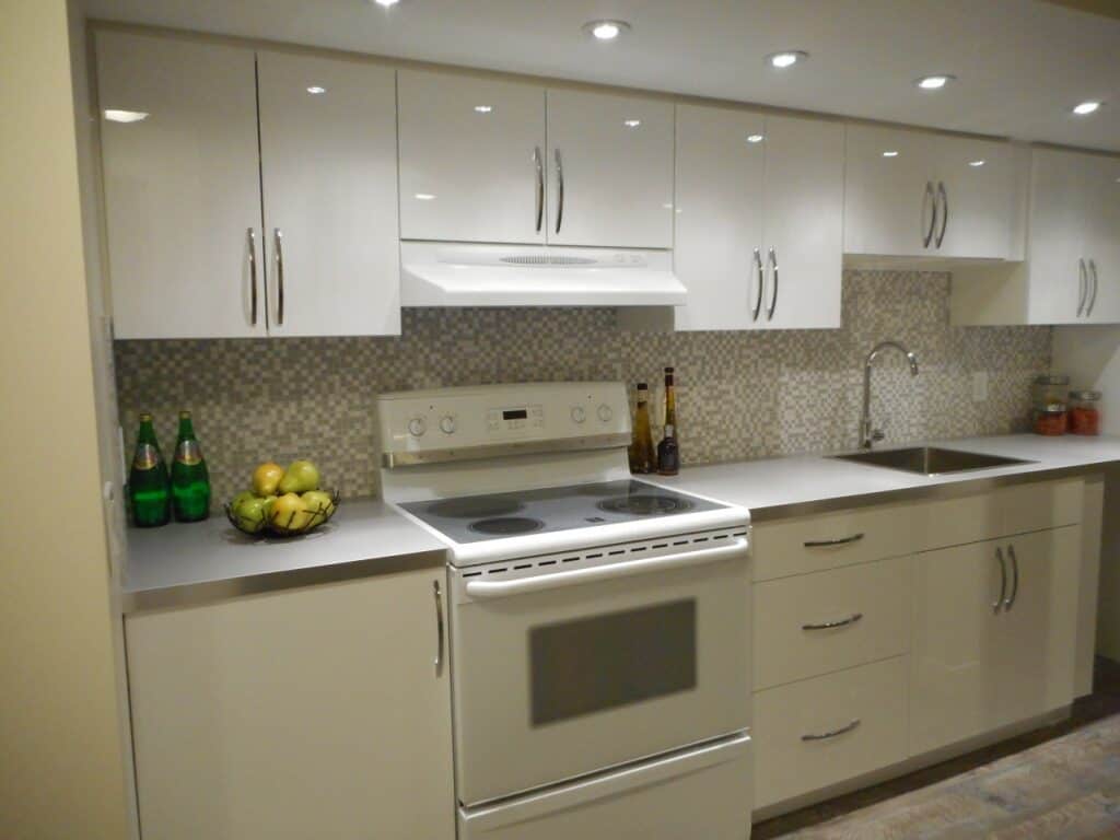 Bright white kitchen cabinets, new stainless look countertops, marble and glass backsplash all help to make this kitchen renovation a success
