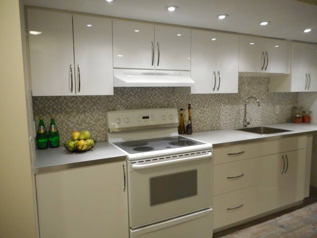 A kitchen with a stove, sink, and white cabinets