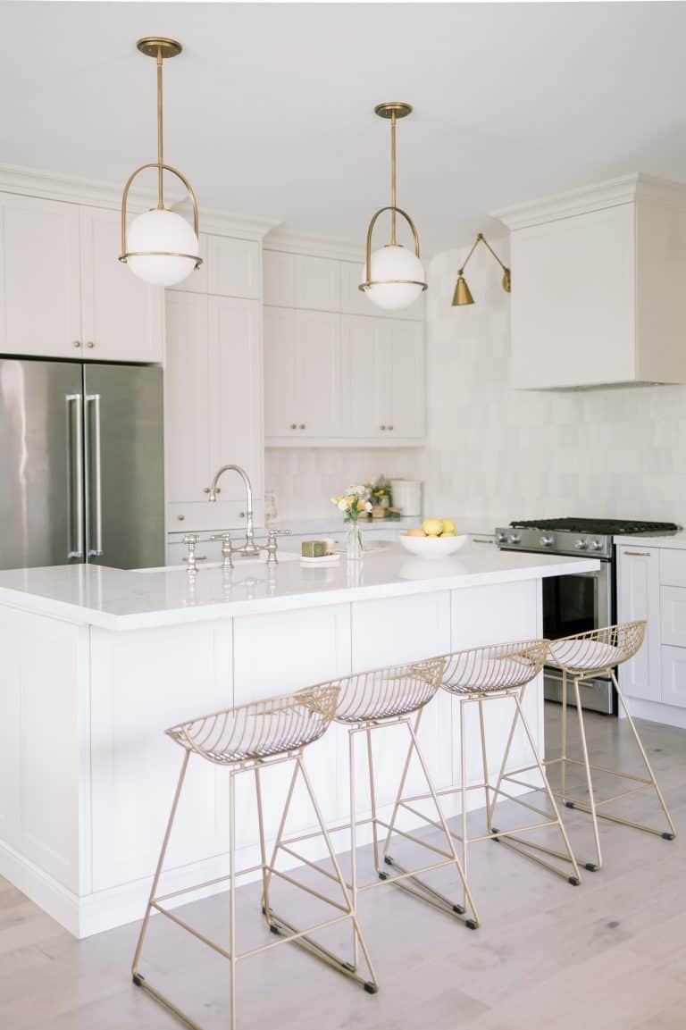 A kitchen with white countertops and steel chairs