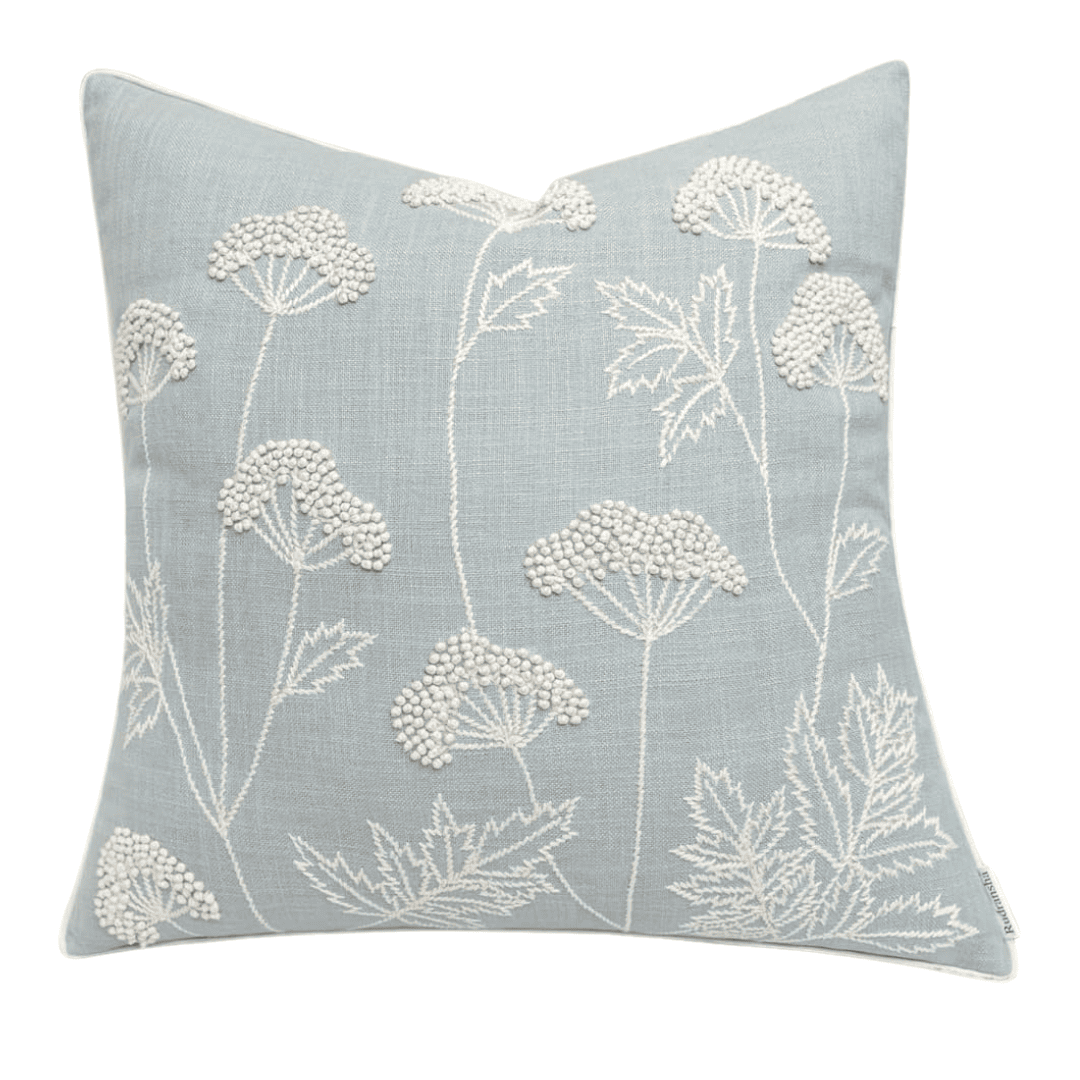 Hand-embroidered cotton cushion in soft white and cream. Adds gentle texture to a coastal blue bedroom.
