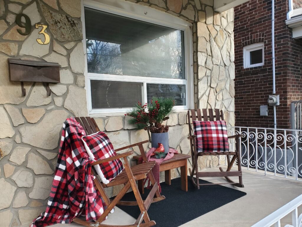 Cozy winter porch decorating - Red and black and white checked pillows and a throw on chairs on a veranda