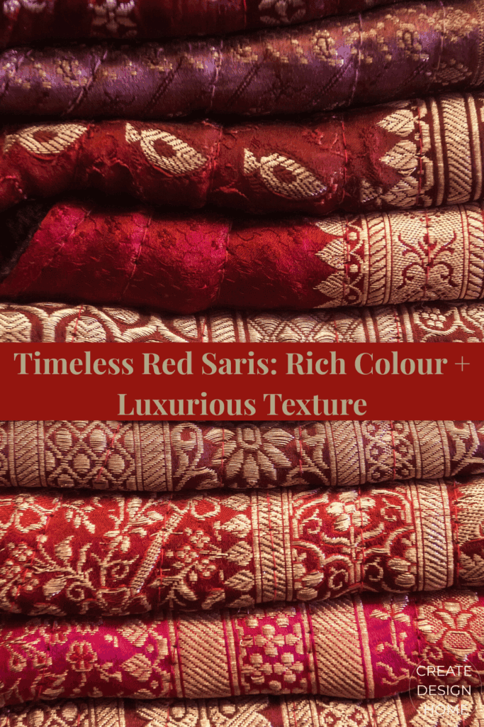 Stacked red saris with ornate patterns and luxurious woven textures.