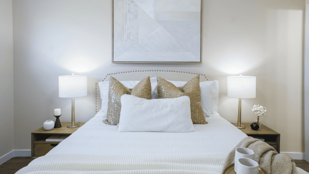 Neutral staged bedroom with white bedding, upholstered headboard and soft layered styling