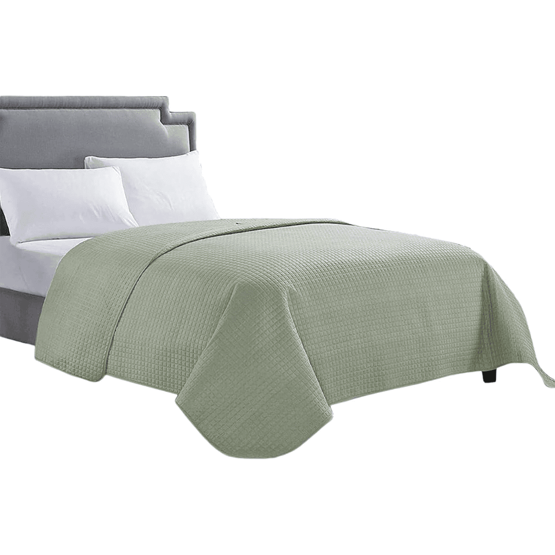 Sage green quilted bedspread on neutral staged bedroom bed