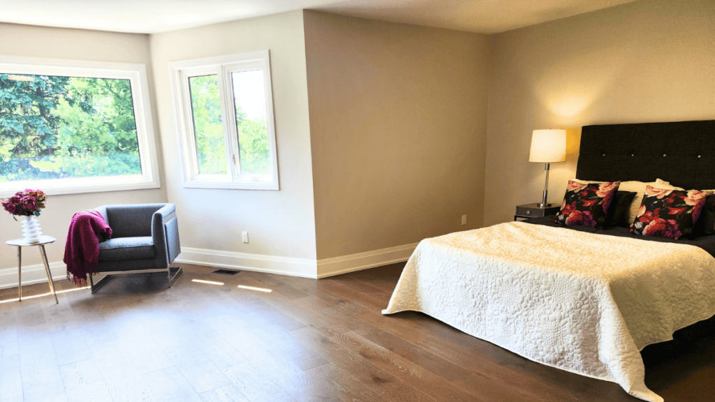Spacious staged primary bedroom with sitting area and natural light