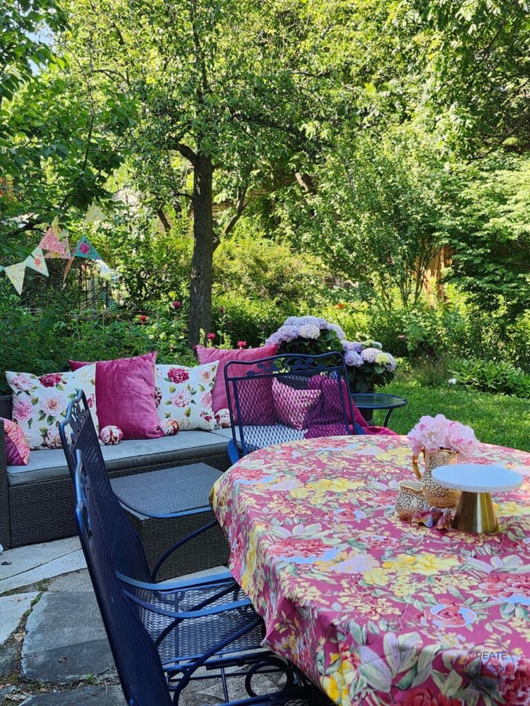 Outdoor garden with dining table and lounge seating arranged to create conversation areas for a summer tea party.