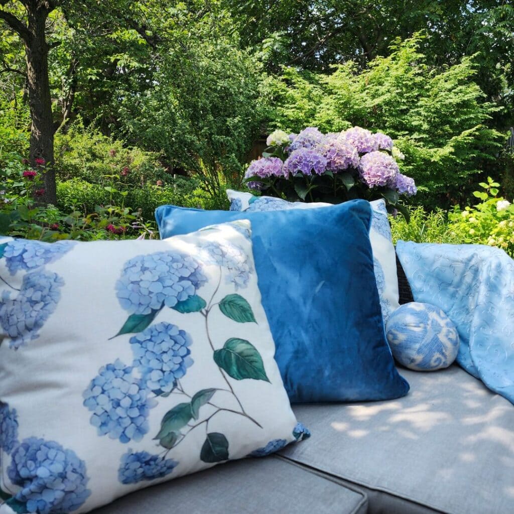 Blue and hydrangea-print cushions on an outdoor garden sofa