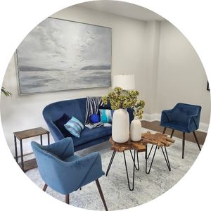 Professionally staged living room with blue accent chairs and neutral décor.