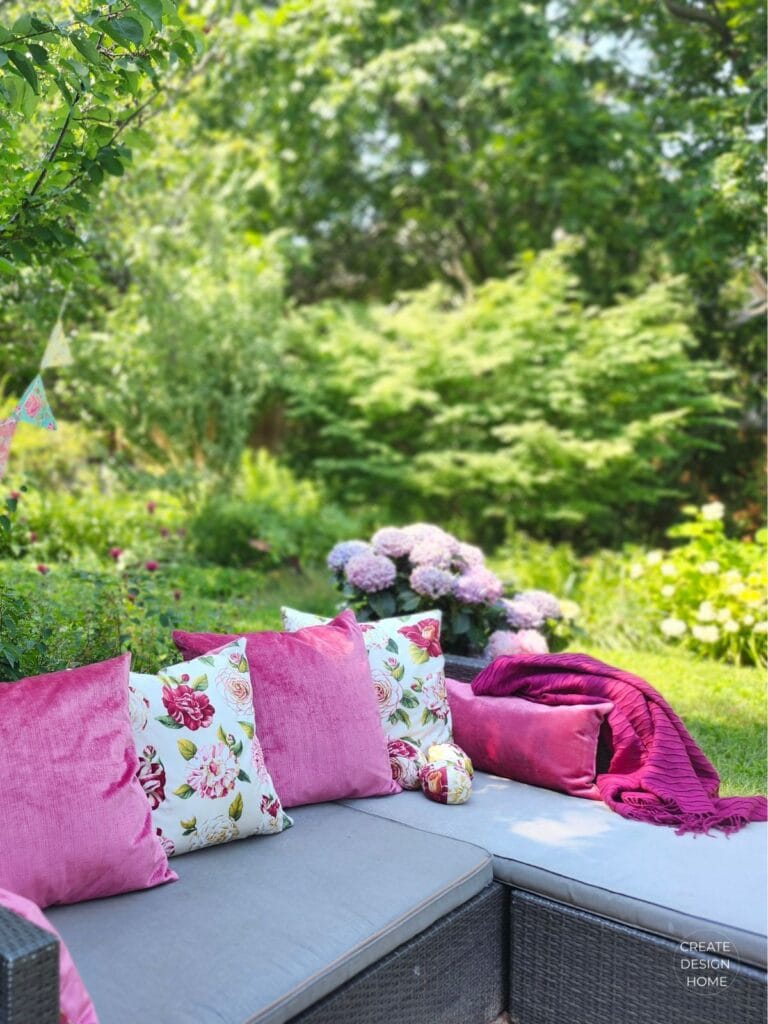 Outdoor garden seating styled with pink velvet cushions and hydrangeas for an English country garden tea party.