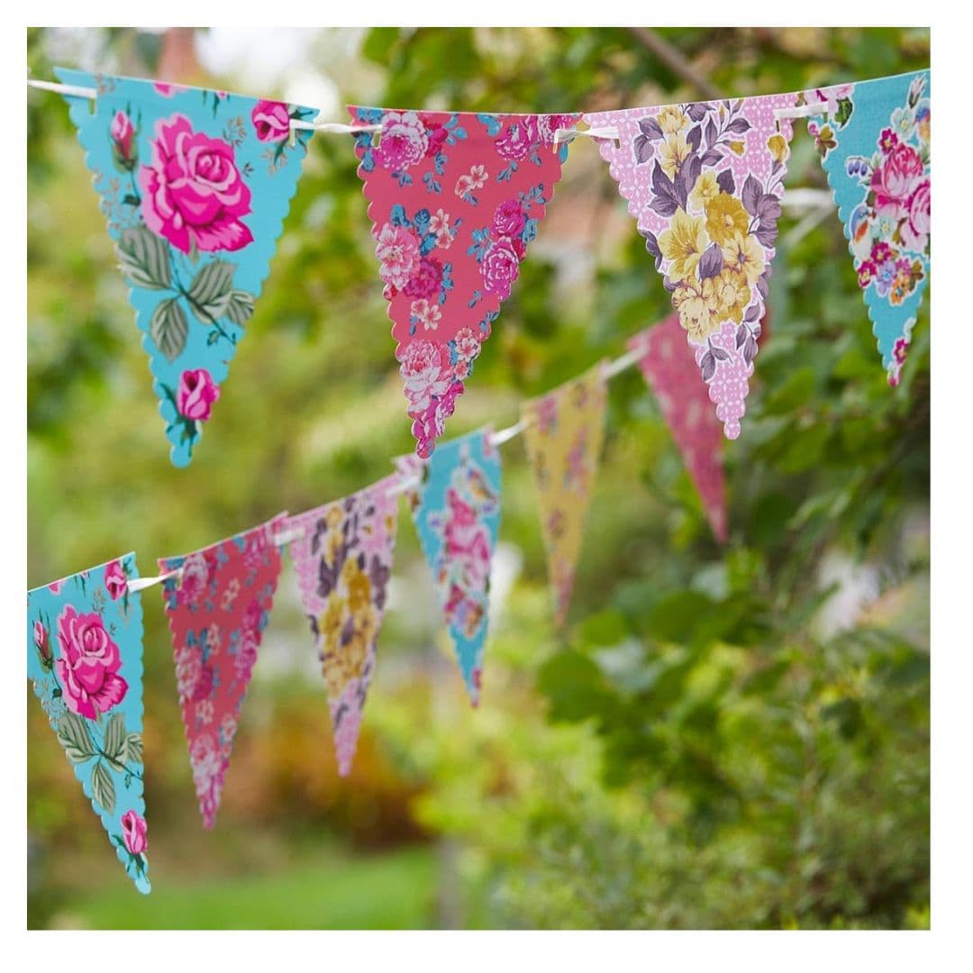Vintage floral bunting hanging between trees in an English country garden.