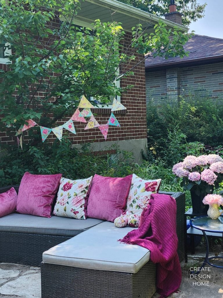 Vintage inspired floral bunting decorating an English country garden with pink cushions and hydrangeas