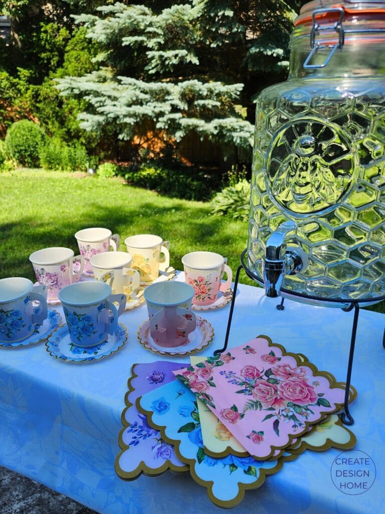 Vintage inspired paper tea cups with matching saucers and floral serviettes displayed at a summer garden tea party beverage station