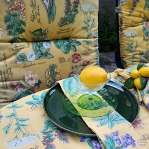 Matching botanical fabric used for an outdoor cushion, tablecloth and napkin with a lemon place setting