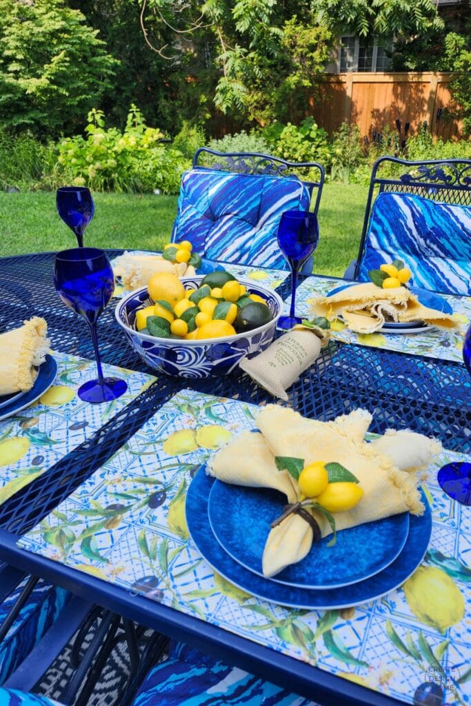 Summer table decorated with lemons, blue plates, cobalt glasses and lemon-print placemats