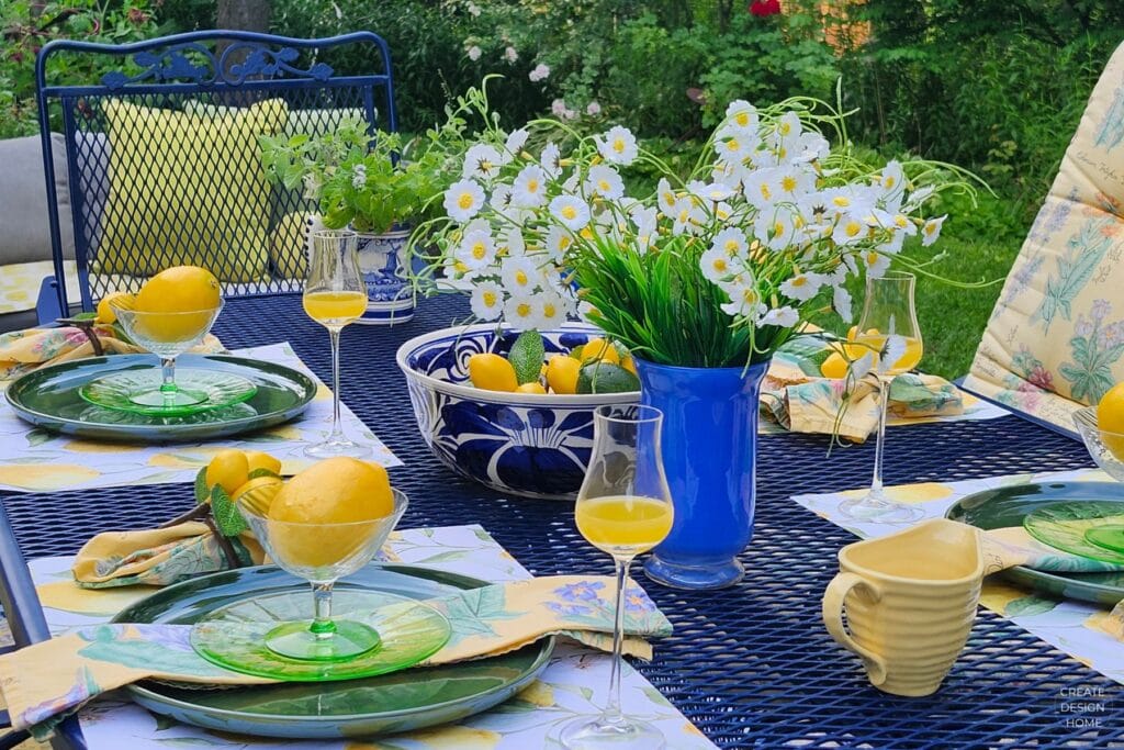 Lemon-inspired outdoor table with fresh lemons, white flowers, green plates and blue accents
