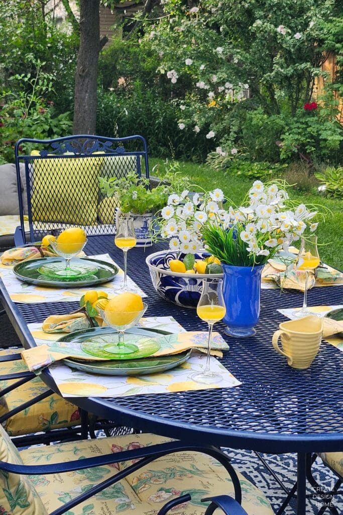 Lemon-inspired summer table with blue glassware, green plates, white flowers and fresh lemons
