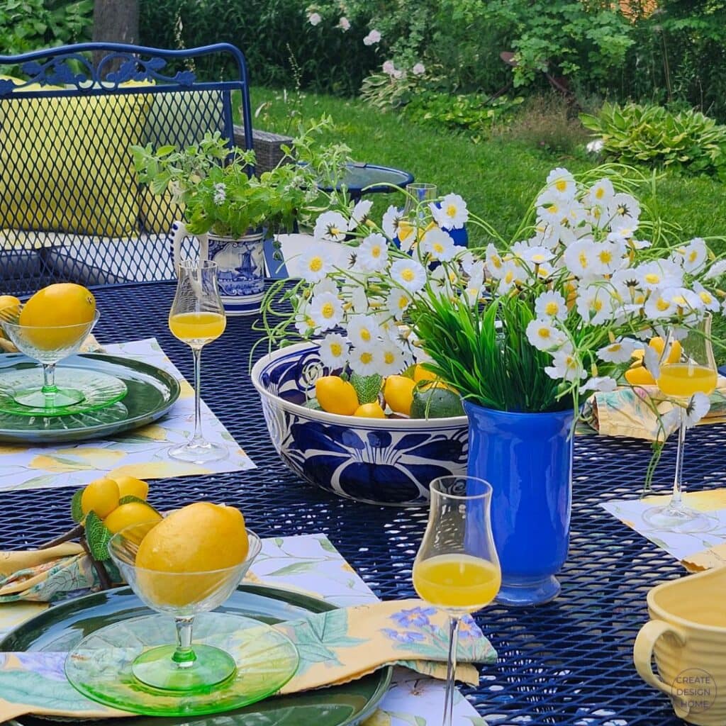 Lemon-inspired summer table with fresh lemons, blue and white bowls, green glassware and white flowers