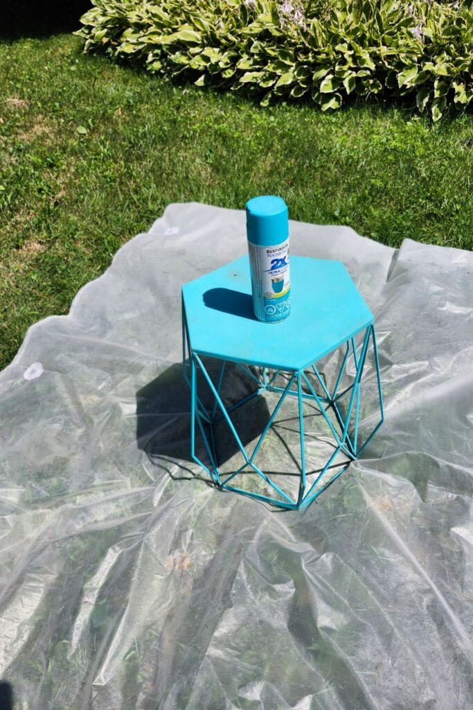 Small outdoor side table being spray painted turquoise