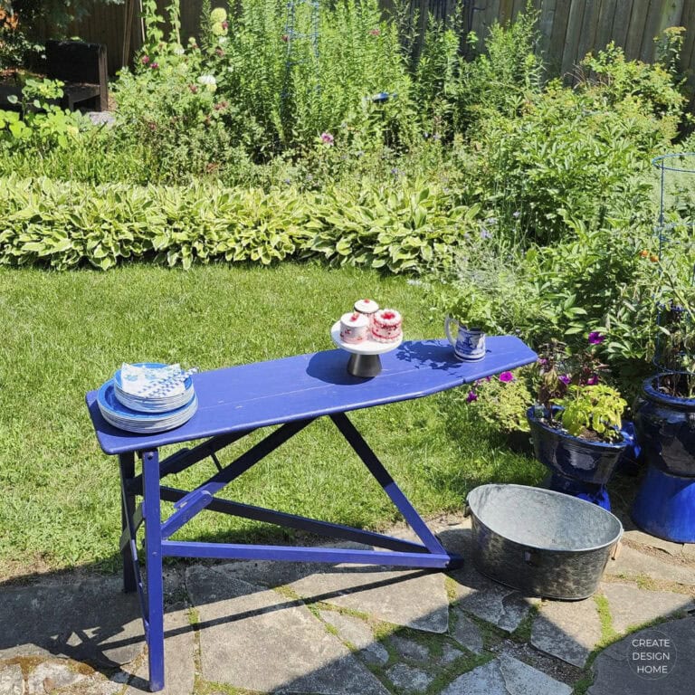 Blue vintage ironing board repurposed as an outdoor serving table