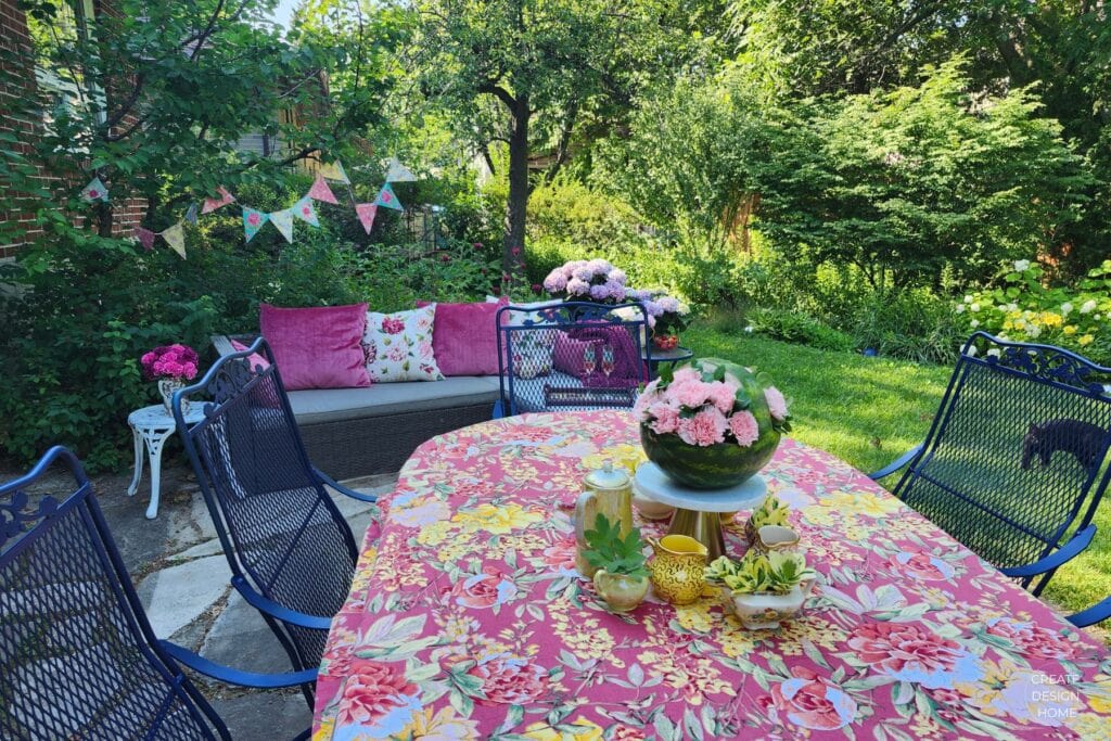 Colourful garden party table set with flowers and outdoor seating in a summer garden.