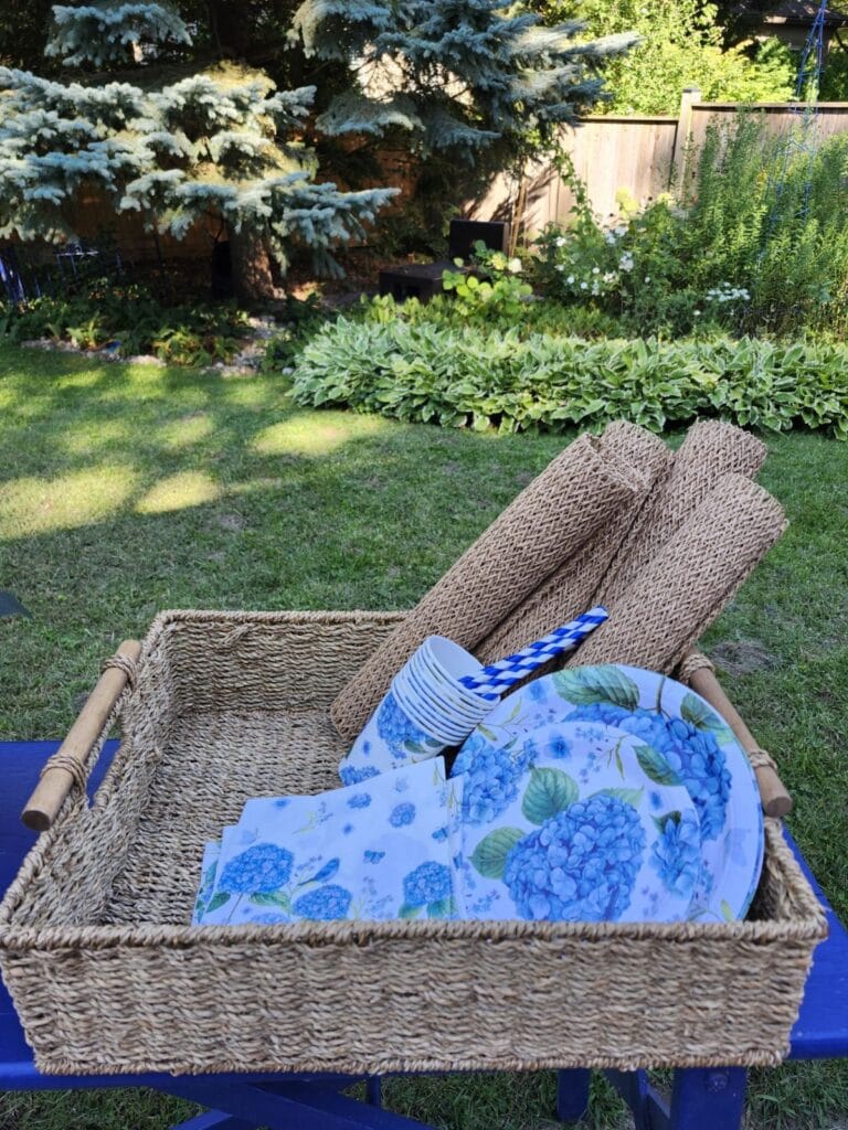 Basket filled with hydrangea plates, napkins and woven placemats for a summer garden party
